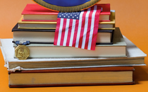 detail of photo of stack of books, American flag, medal and plate from Howard University on orange background