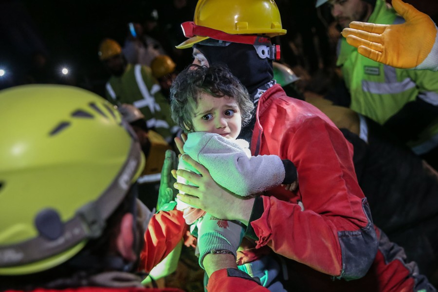 Rescue workers carry a young child away from a wrecked building.