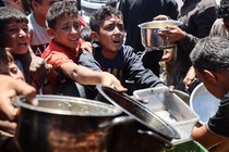Palestinian youths shove to get a ration of hot food at a charity kitchen in Gaza City