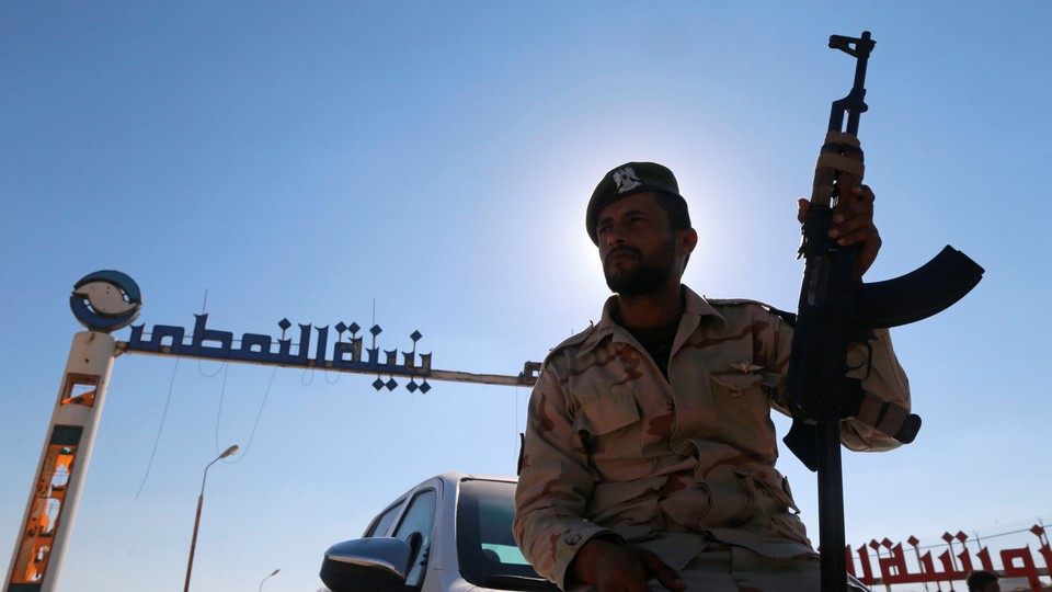 A member of Libyan forces loyal to eastern commander Khalifa Haftar holds a weapon as he sits on a car in front of the gate at Zueitina oil terminal, west of Benghazi, Libya, on September 14, 2016.