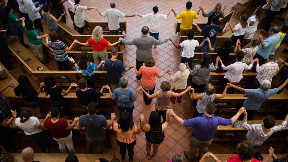 People stand and hold hands in a church.