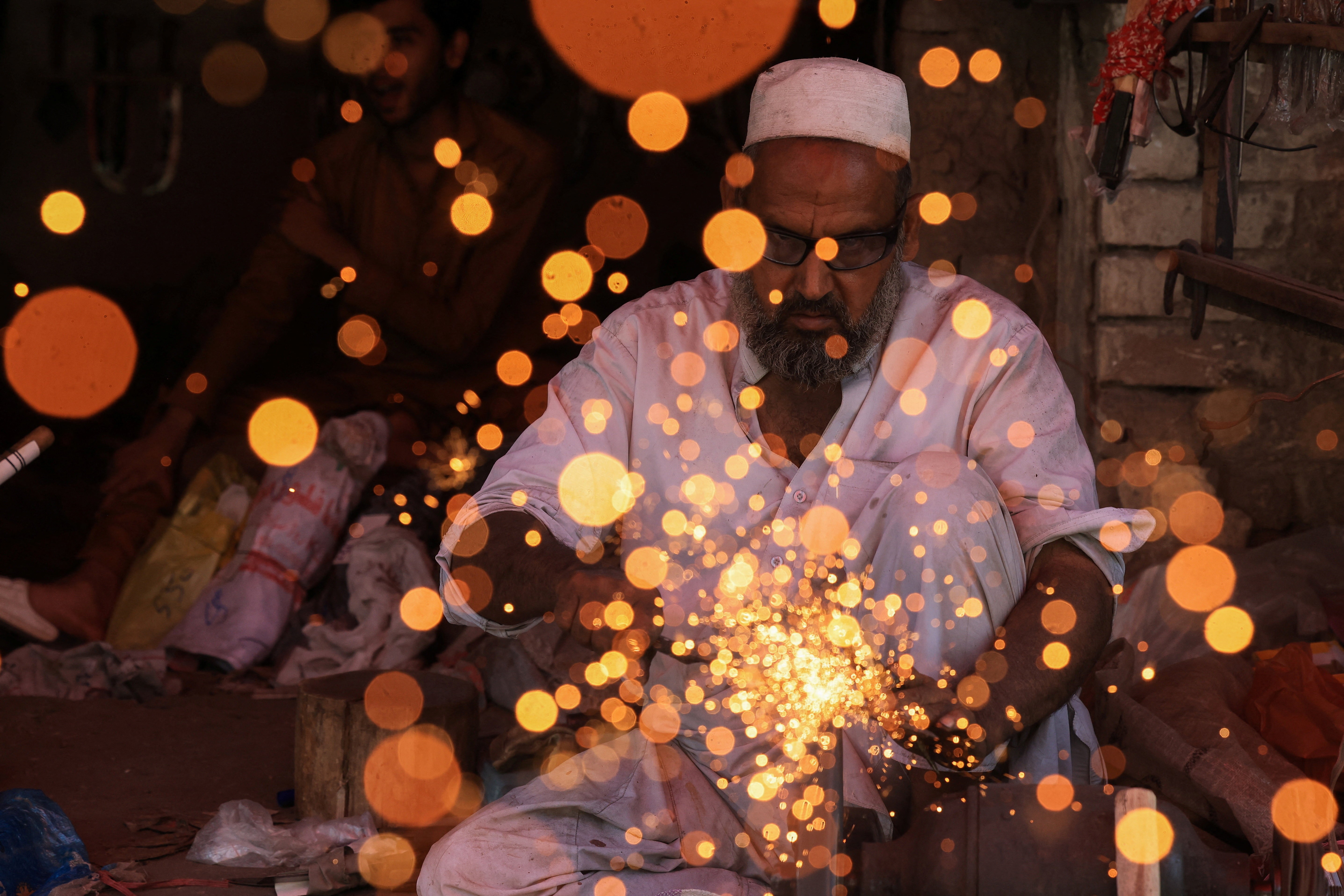 Sparks fly as a man sharpens a cleaver.
