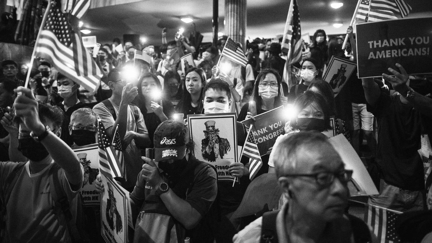 Demonstrators hold placards and American flags during a rally in support of the Hong Kong Human Rights and Democracy Act, in Hong Kong, China, on Monday, Oct. 14, 2019.
