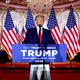 Trump standing behind a lectern with a sign that says "Trump 2024"
