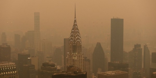The Chrysler Building and other New York skyscrapers stand beneath an orange, smoky sky.