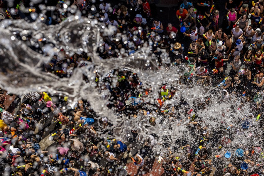 A view looking down at a large crowd, as water is thrown from a bucket.