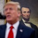 Donald Trump standing in front of a painting of Abraham Lincoln
