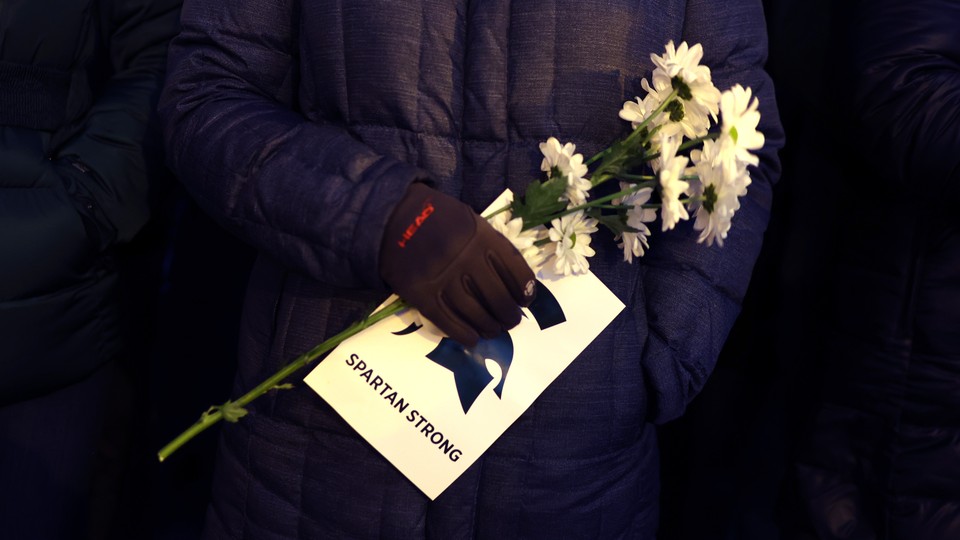 A photo of a gloved hand holding flowers and a piece of paper that reads, "Spartan strong"