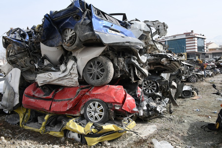 Destroyed cars, pulled from the rubble, are stacked in piles.