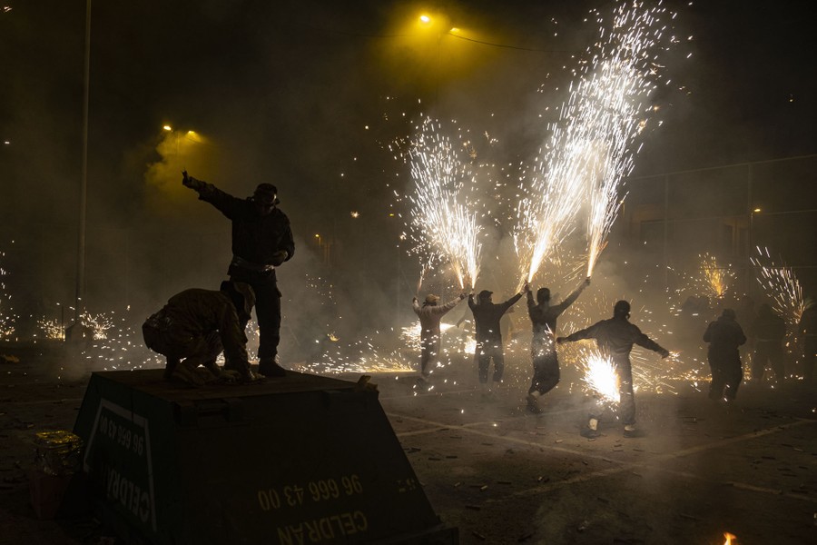 Several people run about while holding sparking fireworks in their hands.