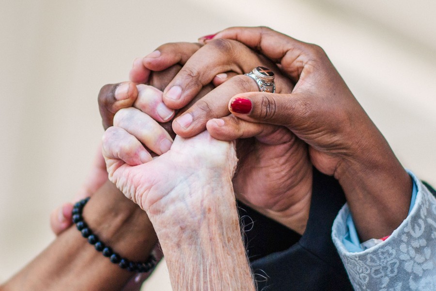 The hands of at least four people are seen held together in the air.