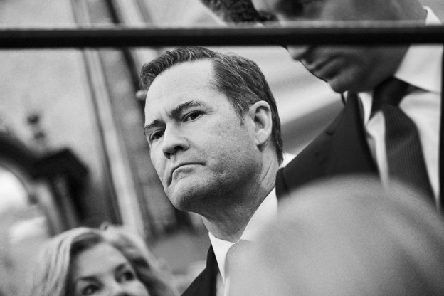 Michael Waltz looks on, beside Stephen Miller, in a black and white photo taken slightly at a tilt
