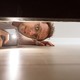 Man looking under his bed with a flashlight
