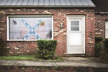 A Confederate flag hangs in the window of a house. 