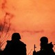 A photo showing three soldiers silhouetted against a sunset