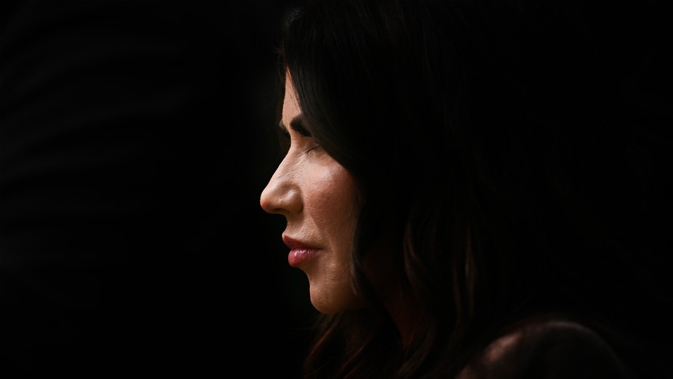 Photograph of Kristi Noem's face in profile against a black background.