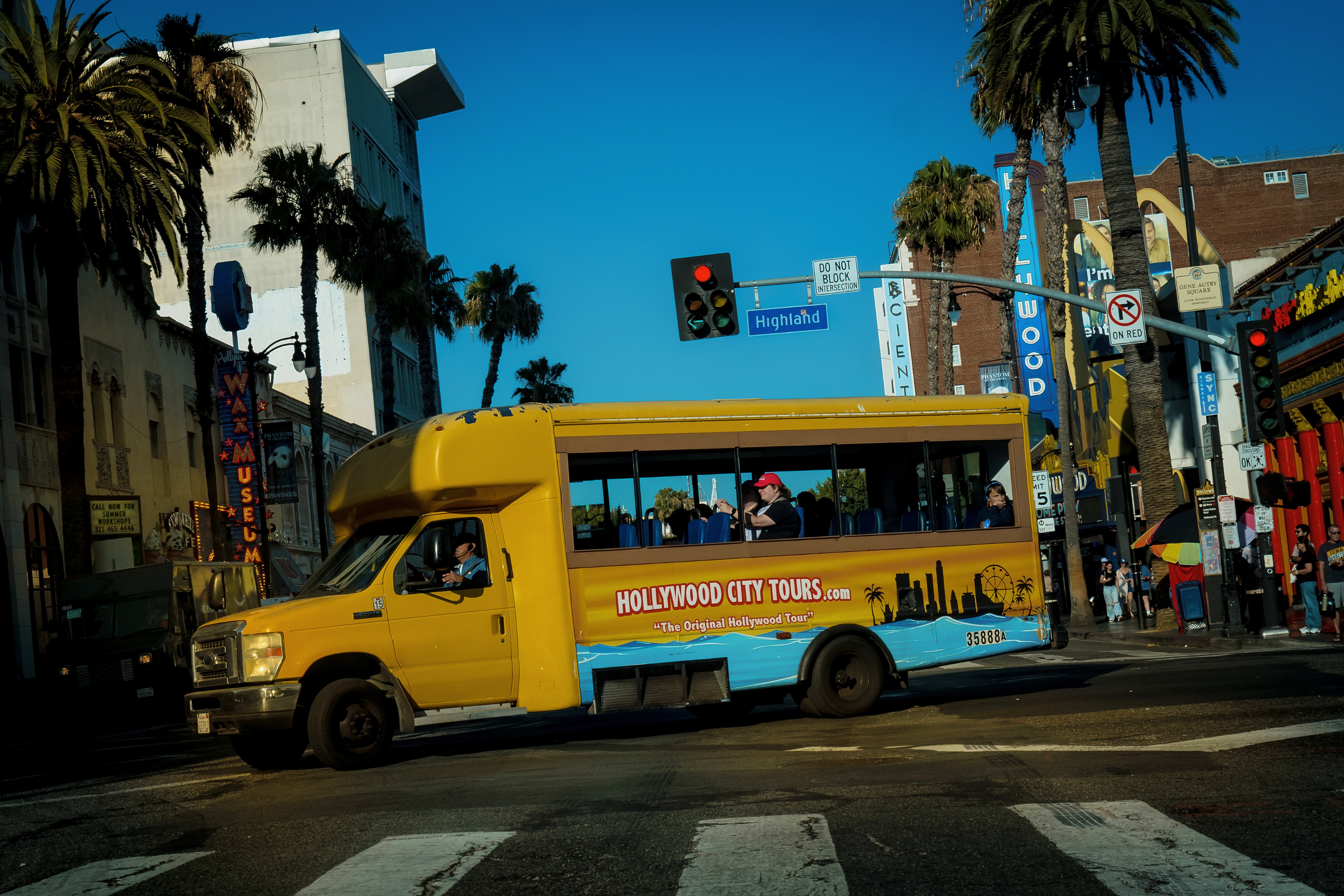 photo of intersection at Highland with bright yellow Hollywood City Tours bus