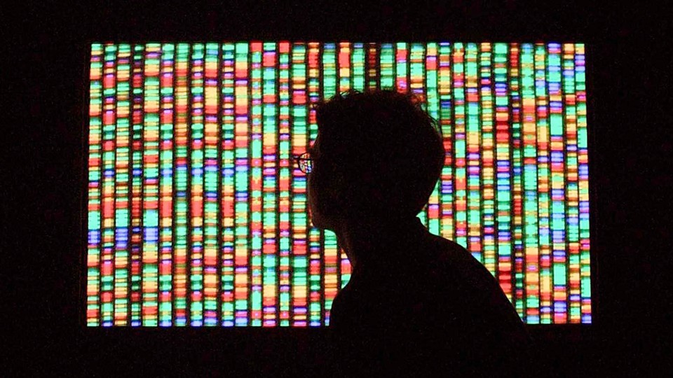 Shadow of a person's head in front of a screen showing DNA