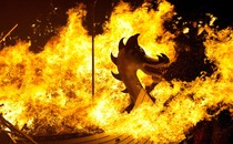 A Viking ship decorated with the head of a dragon is engulfed in flames.