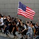 Hong Kong protesters hold up five fingers and brandish an American flag during a march.