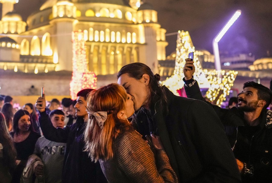 A couple share a kiss as they celebrate New Year's Eve in a city square.