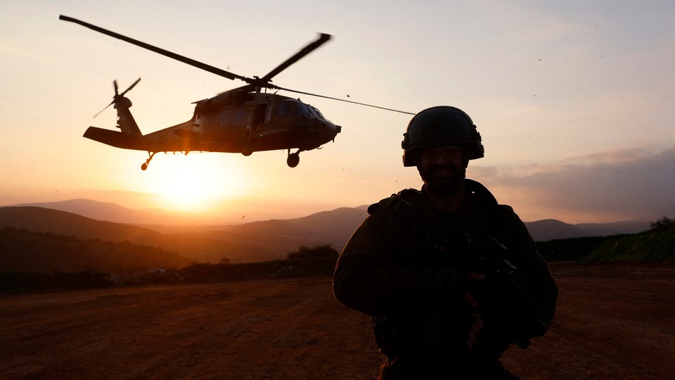 An Israeli soldier looks on as a military helicopter hovers.