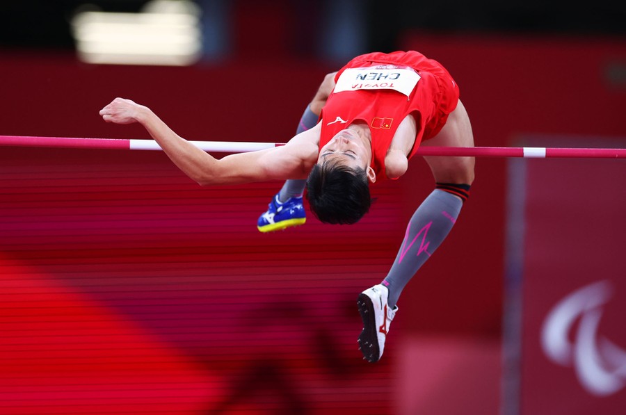 An athlete leaps over a bar during a men's high jump.