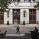 A photo of people sitting at tables in a leafy courtyard in front of a building on Columbia University's campus
