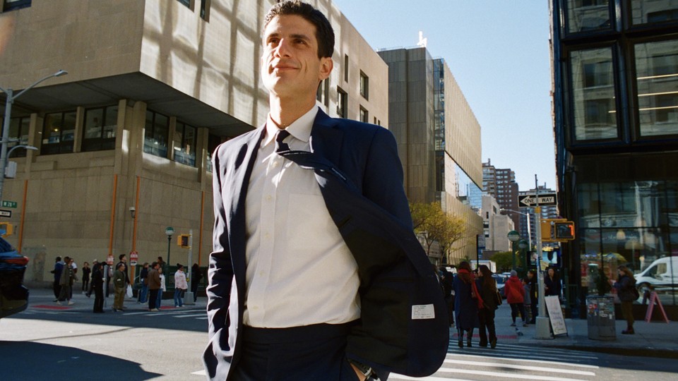 An image of a smiling Jack Schlossberg walking on a crosswalk in Manhattan.