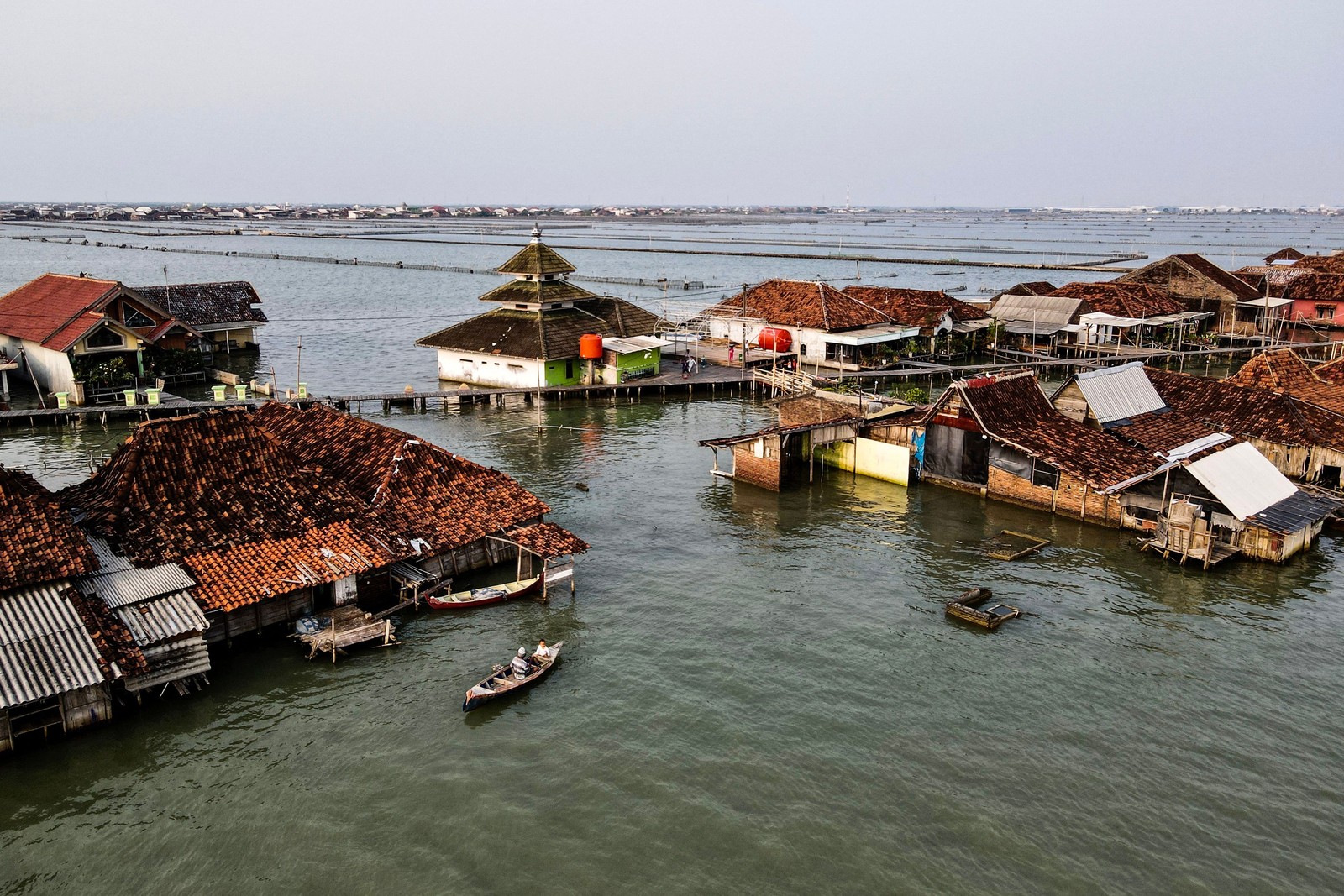 An elevated view of a cluster of houses surrounded by seawater, connected by boardwalks