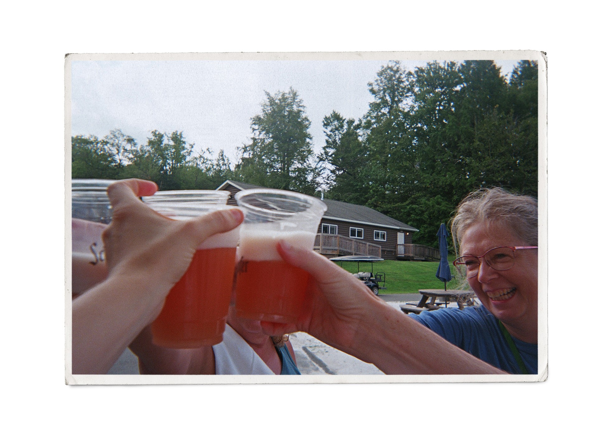 a group of campers hold up their drinks outdoors