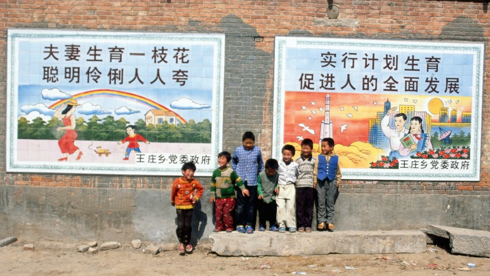 A group of young boys stands close to two large posters extolling the one-child policy.