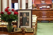 An image of Representative Melissa Hortman's seat in the Minnesota State Capitol building with flowers and a framed photo of her.