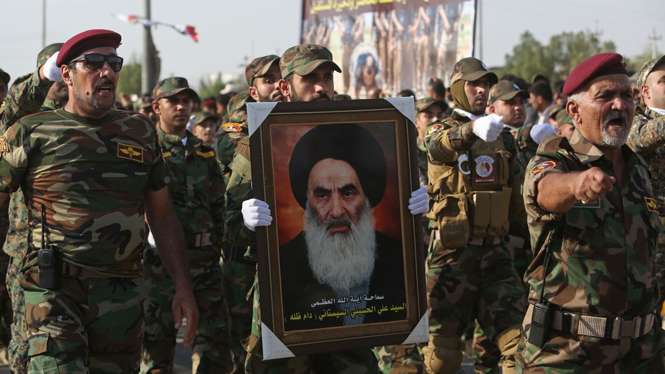 Members of the Abbas combat squad, a Shiite militia group, carry a picture of Grand Ayatollah Ali al-Sistani.