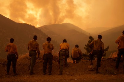 a row of people look out on the Line Fire in the hills