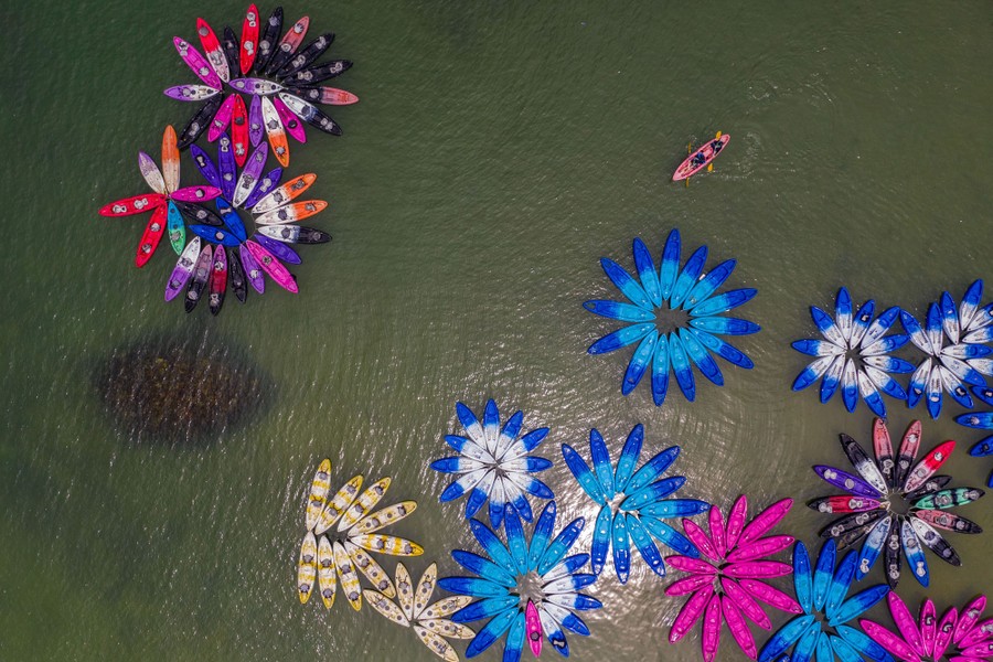 An aerial photo of many colorful kayaks floating in a bay