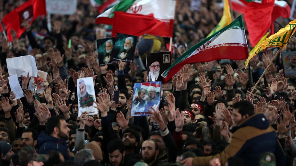 Iranians carry pictures of Iranian Supreme Leader Ayatollah Ali Khamenei and Qassem Soleimani during Soleimani's funeral.