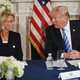 President Donald Trump sits at a table next to Education Secretary Betsy DeVos. 
