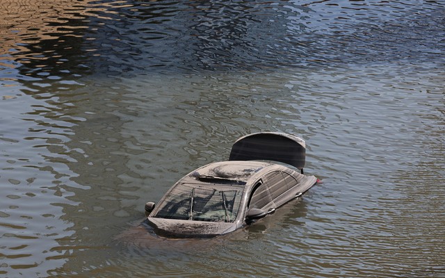 An abandoned vehicle floats in floodwater.