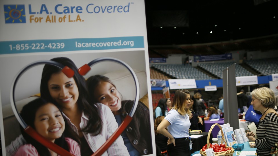 Two women converse behind a sign for the L.A. Care Health Plan.