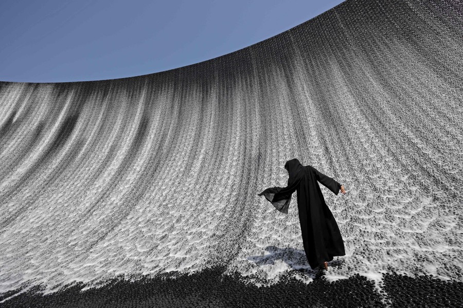 A woman walks onto a wall-like water feature.