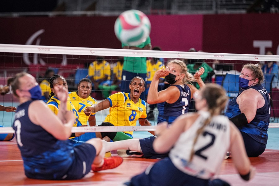 Two teams of volleyball players take part in a sitting volleyball match.