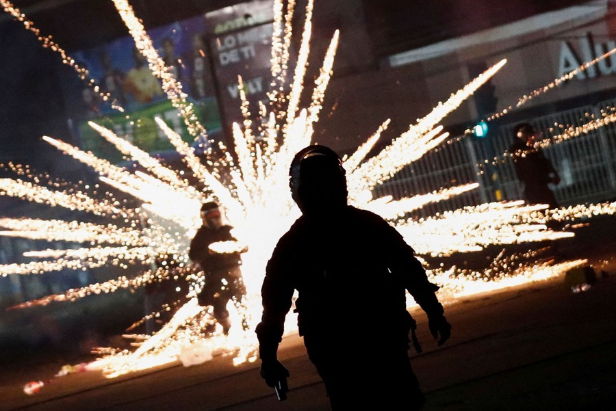 Several riot police officers are caught in a fireworks explosion.