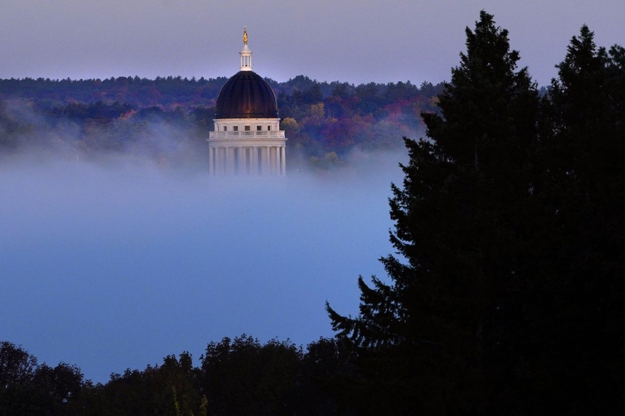 The Maine State House towers over a fog bank.