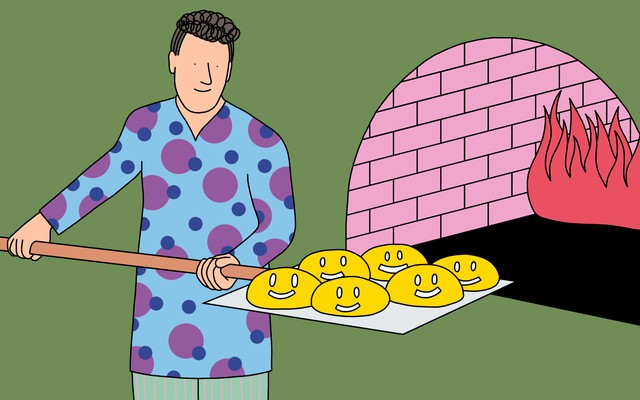 A baker loads a batch of bread-dough-shaped smiley faces into a brick oven.