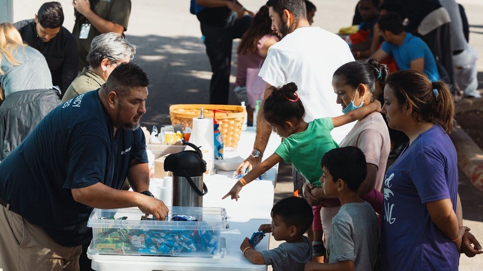 Groups of migrants receive food outside the Migrant Resource Center in Texas. 