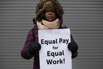 A woman holds a sign saying "Equal pay for equal work"