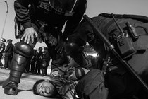Black-and-white image of California Highway Patrol officers holding to the ground and arresting a demonstrator at the L.A. protests.