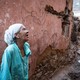 A person reacts, standing beside a damaged wall and piles of rubble, after an earthquake.