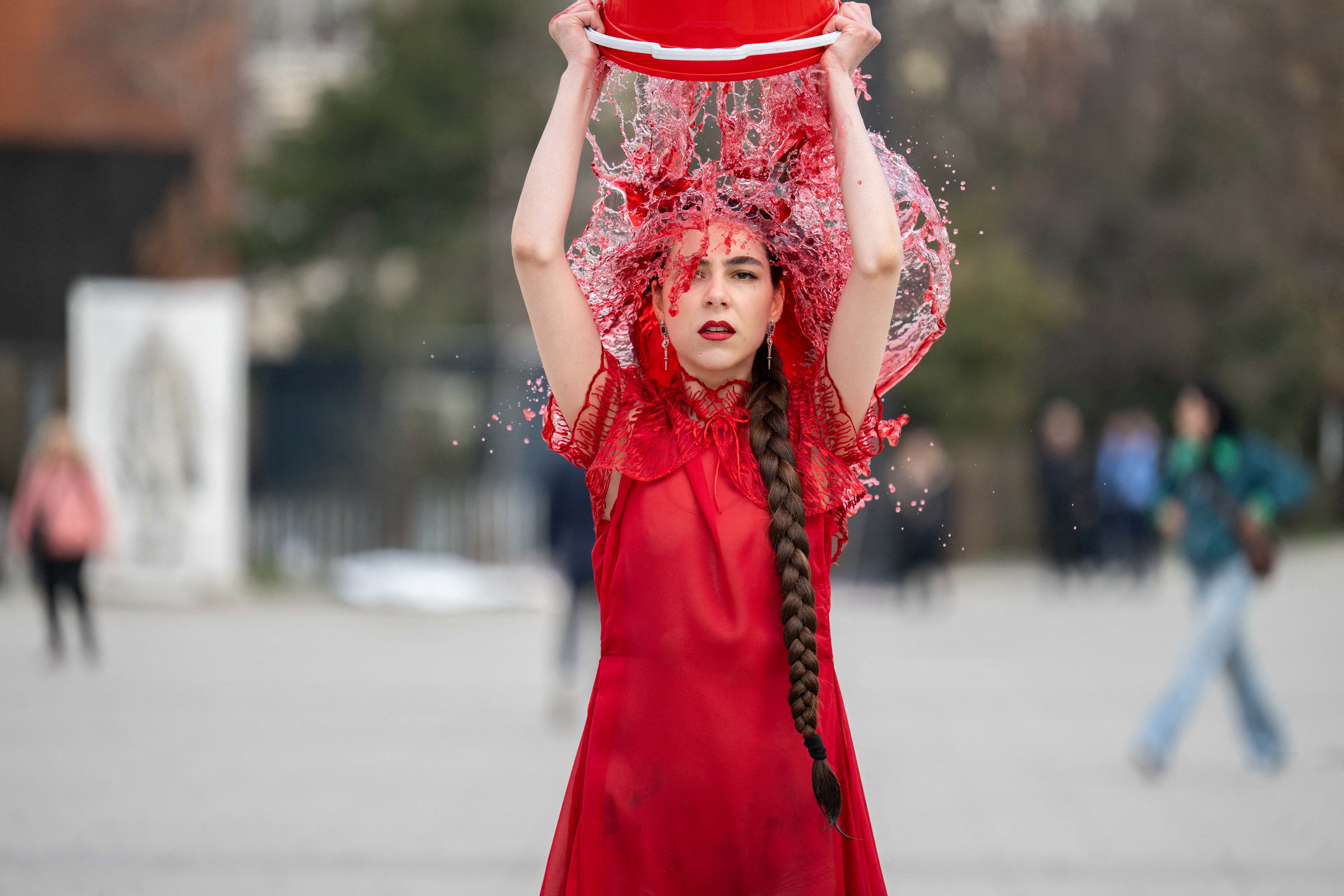 A performer pours a bucket of colored water over their head.